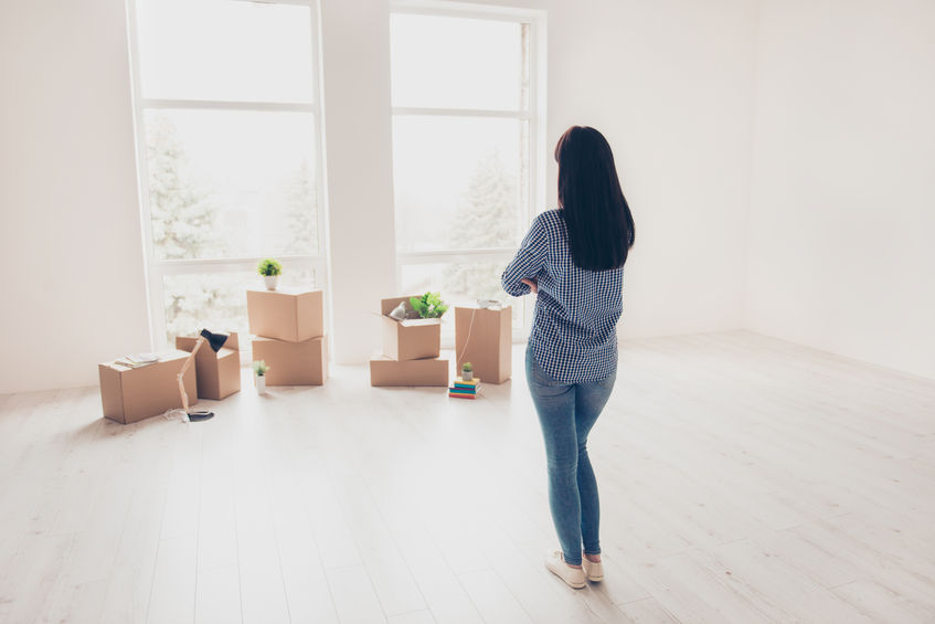 Woman in first apartment, looking at open space and moving boxes