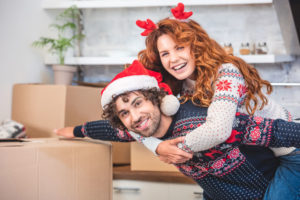 Happy young couple piggybacking and smiling at camera while moving during the winter holidays