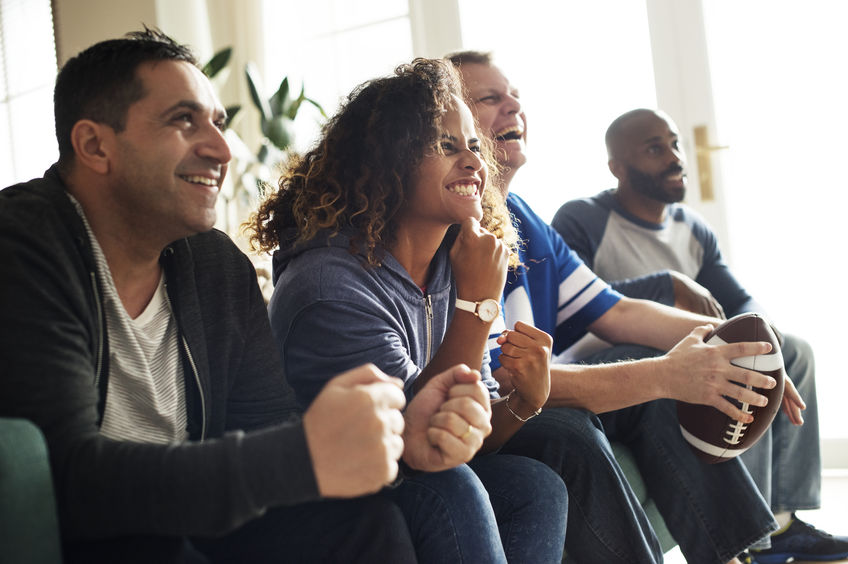 Friends in apartment, cheering for team and watching Sunday football game on TV