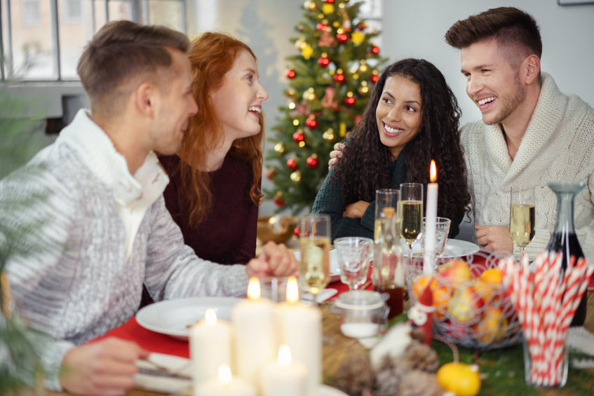 friends sitting around a wooden table and enjoying christmas dinner together